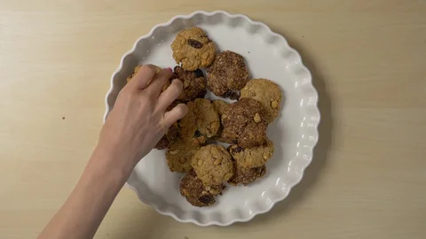 Female hands arrange cookies on a plate. Several people take cookies Stock Footage