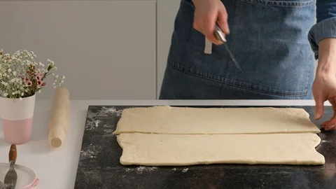 Female hands of a baker cut the dough with a thin knife in the home kitchen Stock Footage 128075798