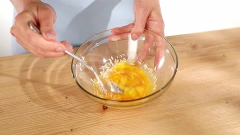 Female hands beat eggs with grated cheese in a bowl. close up. Stock Footage 245346416