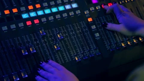 Female hands behind the mixing console mixes tracks for disco in color lighting Stock Footage 104670569