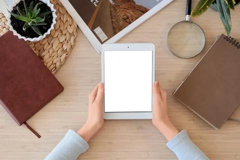 Female hands with blank tablet computer and notebooks on table, top view Foto stock