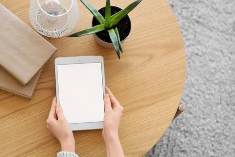Female hands with blank tablet computer on table at home, top view Stock Photos