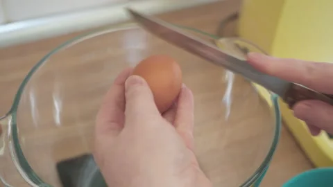 Female hands break the egg with a knife and separate the yolk from the protein. Stock Footage 132086439