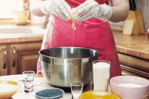 Female hands break an egg to make cake dough. Stock Photos