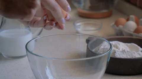 Female hands break an egg into a transparent bowl. Stock Footage 112879982