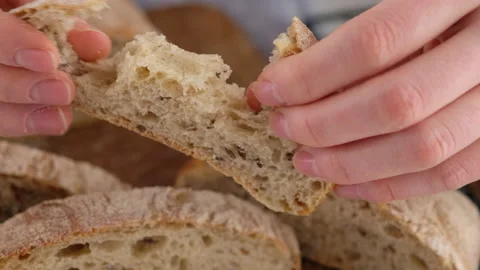 Female hands breaking a piece of bread. Sliced bread lies on a wooden board Video stock 145492001