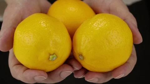 Female hands bring three lemons Stock Footage 122943919