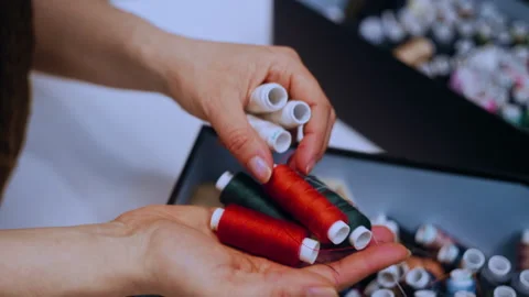 Female Hands Browsing a Thread Assortment Box and Picking a Red Bobbin Vídeos de archivo 335931181