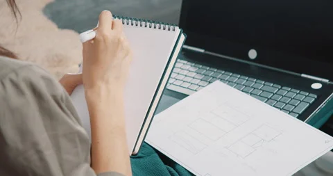 Female hands checking data in a drawing on paper and writing them in a notebook Stock Footage 131109934