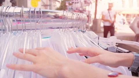 Female hands choosing blouses and t-shirts in the shop Stock Footage 80911166
