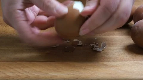 Female hands close-up clean boiled chicken egg. Home kitchen wooden table. Stock Footage 346800506