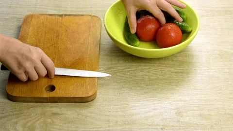 Female hands close-up. Cut tomatoes and cucumbers on a wooden cutting board. Stock Footage 130873754