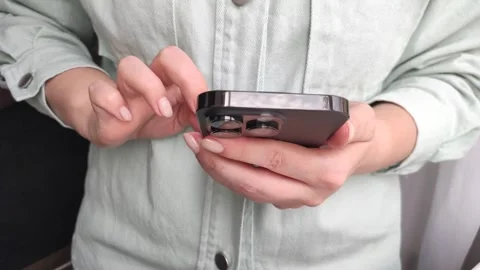 Female hands close-up typing a message on a smartphone, a young girl typing in Stock Footage 255040631