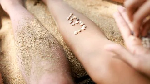 Female hands collect pattern of shells and sand, close up. Video. Pieces of Stock Photos