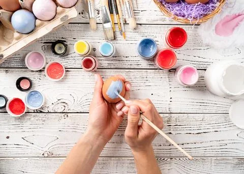 Female hands coloring easter eggs with pastel paints, top view flat lay Stockfoto's