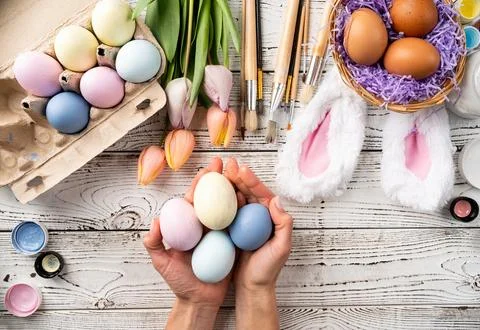 Female hands coloring easter eggs with pastel paints, top view flat lay Stock Photos