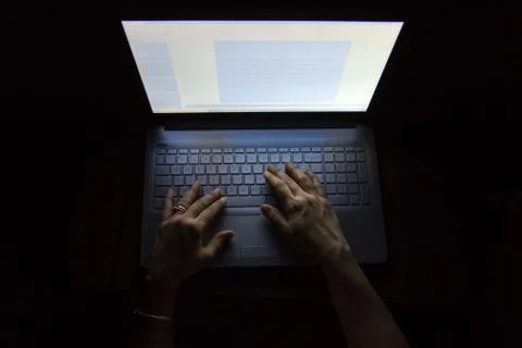 Female hands on a computer, working in the dark. Stock Photos