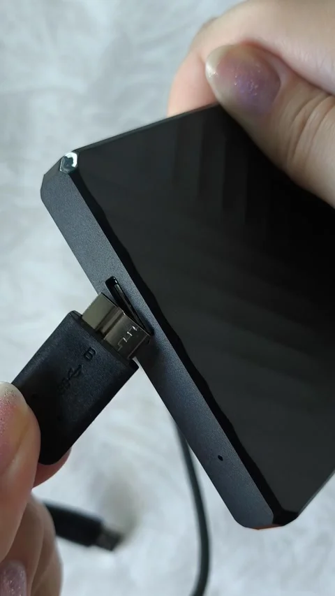 Female hands connect the cable to an external HDD hard drive. Additional memory Stock Footage 313980277