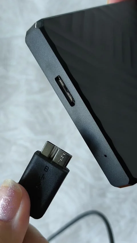 Female hands connect the cable to an external HDD hard drive. Additional memory Stock Footage 313980346