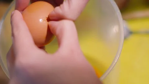 Female Hands Cracking Chicken Egg into Measuring Jug to Whisk and Make Stock Footage 318224322