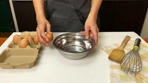 Female hands cracking an egg over silver bowl. 4K video. Stock Footage 130850232
