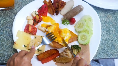 Female hands cut benedict egg with hollandaise sauce with fork and knife. Plate 動画素材 200880881