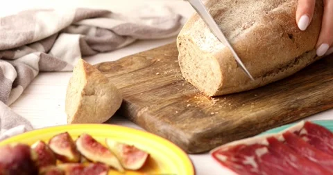 Female hands cut bread with a knife on a cutting board. Stock Footage 249334622
