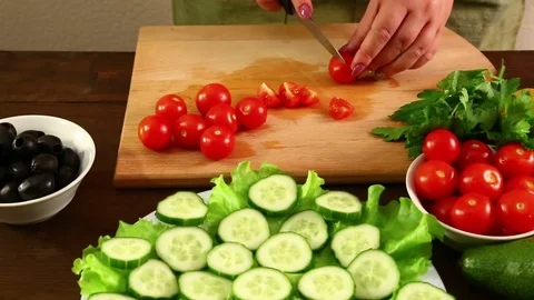 Female hands cut cherry tomatoes to make vegetable salad. Stock Footage 80544252