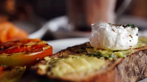 Female hands cutting avocado mashed toast an poached egg healthy breakfast Stock Footage 126393094