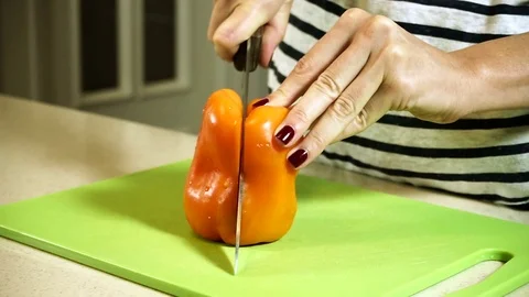 Female hands cutting bell pepper on the parts on plastic cutting board. HD Stock Footage 70934053