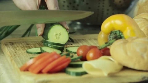 Female hands cutting cucumber into slice with fresh vegetables on background Stock Footage 41402571