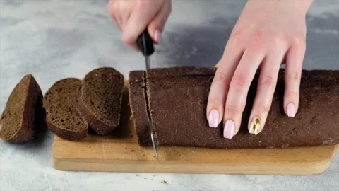 Female hands cutting dark bread with a knife Stock Footage 152717090
