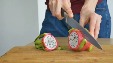 Female hands is cutting a dragon fruit or pitaya with pink skin and white pulp Stock Footage 157180988