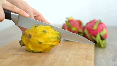 Female hands is cutting a dragon fruit or pitaya with yellow skin and white pulp Stock Footage 170463685