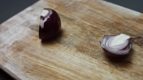 Female hands cutting a fresh red onion into halves on a wooden cutting board. 4K Stock Footage 146922402