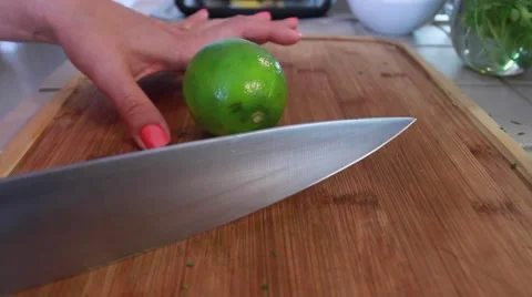 Female hands cutting a green lime in half with a big knife Stock Footage 45281208