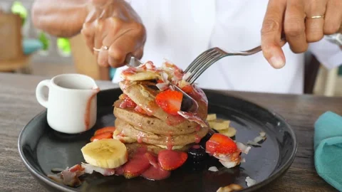 Female hands cutting in a half stack of vegan gluten free pancakes with cutlery Video stock 153458877