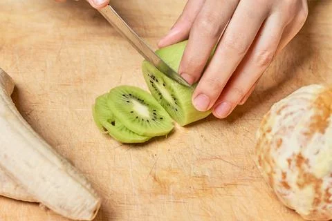 Female hands cutting kiwi fruit Stock Photos