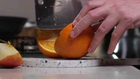 Female hands cutting an orange in the kitchen, close-up Stock Footage 312868763