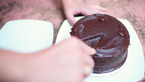 Female hands cutting slice of dark chocolate cake macro closeup on white plate Stock Footage 164664931