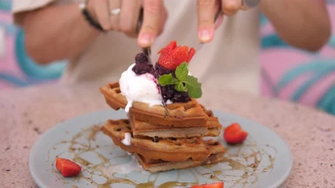 Female hands cutting a stack of belgian waffles topped with ice cream with fork Stock Footage 150298427