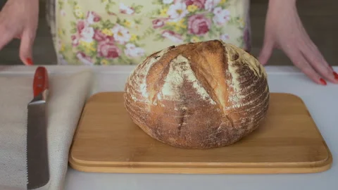 Female hands cutting wheat bread on wooden board Stock Footage 136738611