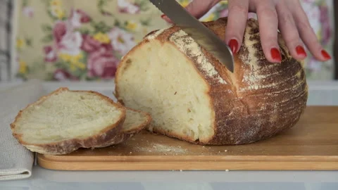 Female hands cutting wheat bread on wooden board Stock Footage 136738775