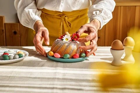 Female hands decorating Easter cake with small colorful chocolate eggs and .. Stock Photos
