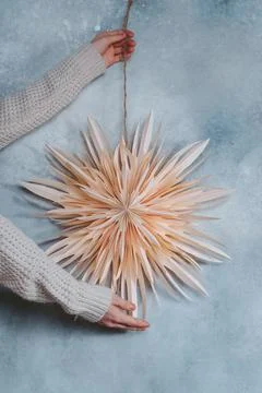 Female hands decorating with homemamde paper star ornament on the wall Stock Photos