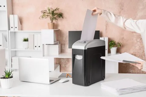 Female hands destroying documents in shredder at office Stock Photos