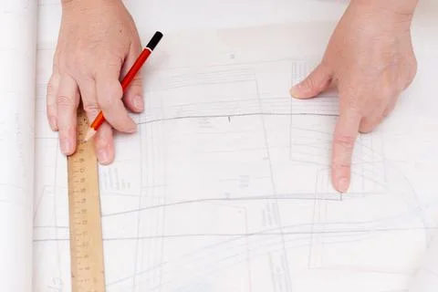 Female hands do the layout of the sewing pattern on paper Stock Photos