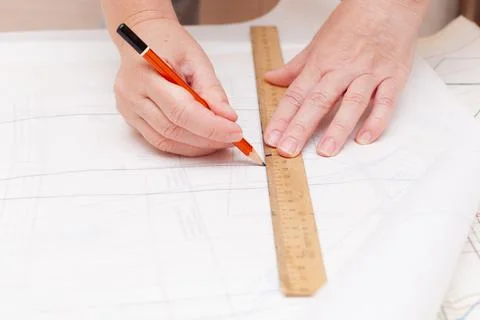 Female hands do the layout of the sewing pattern on paper Stock Photos