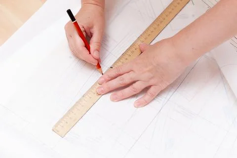 Female hands do the layout of the sewing pattern on paper Stock Photos