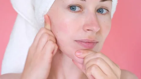 Female hands do self-massage of the face close-up on pink background. Stock Footage 217196422